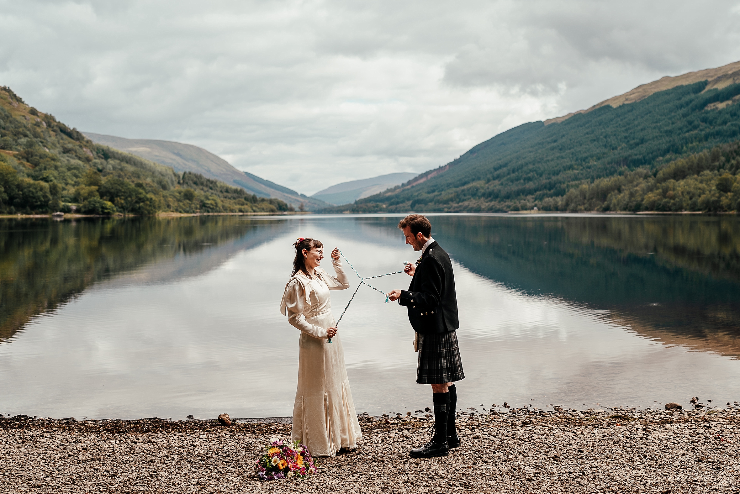a couple tie the knot using a handfast on the shores of loch voil in wedding traditions scotland